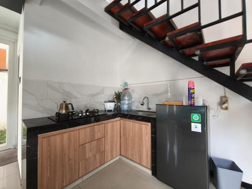a kitchen with a black refrigerator and wooden cabinets at Villa Royal Arois Unit C-01 in Batu