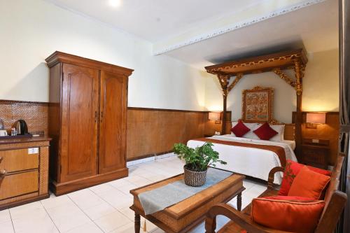 a bedroom with a bed and a table in a room at Puri Dewa Bharata Hotel & Villas in Legian