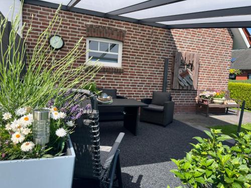 a patio with a table and chairs and flowers at Ferienwohnung Haus Moorblick Garten mit Terrasse Netflix E-Kamin Thermomix in Wiesmoor