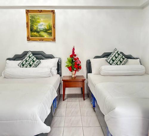 two beds in a room with a vase of flowers on a table at ATVR Juldis Tower Pratunam in Bangkok