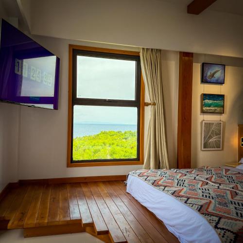 a bedroom with a large window and a television at Aqua Horizon Beachside Condo I Signature Art Suites in Dauis