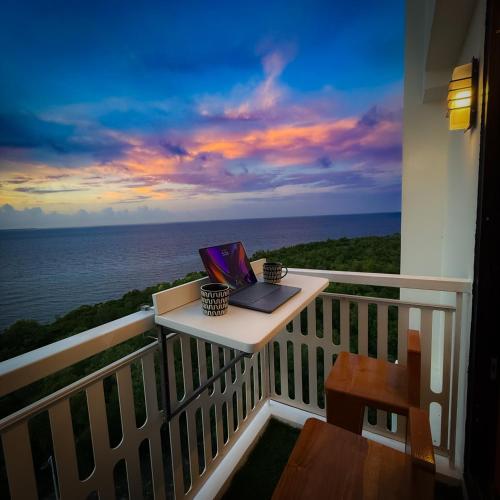 a laptop on a table on a balcony with the ocean at Aqua Horizon Beachside Condo I Signature Art Suites in Dauis