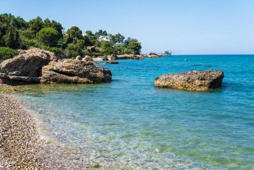 a beach with rocks and blue water and trees at Corte Santa Maria B&B in Vasto