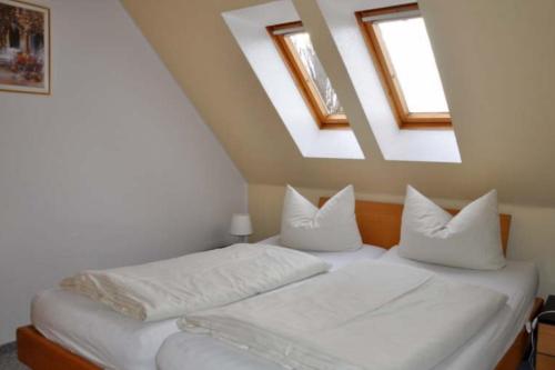 a bedroom with a bed with white sheets and two skylights at Silbermöwe - Sonniger Balkon & Gartenidylle - perfekt mit Hund in Gollendorf