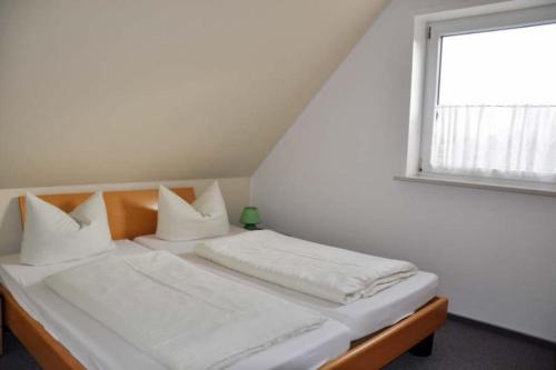 a bedroom with a bed with white sheets and a window at Takelage - Sonniger Balkon & Gartenidylle - perfekt mit Hund in Gollendorf