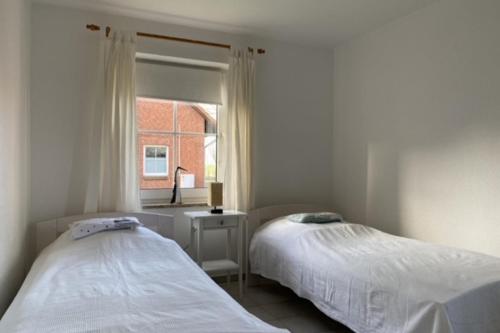two beds in a room with a window at Kamin, Wintergarten & Sonnenterrasse in Wenkendorf auf Fehmarn