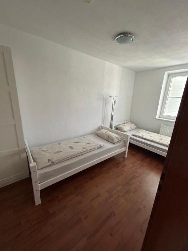 une chambre blanche avec deux lits dedans dans l'établissement Apartment Lara, à Friedrichshafen