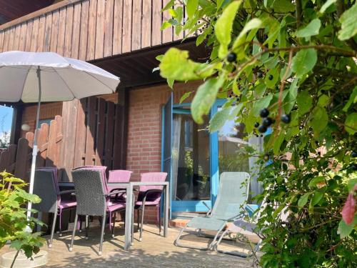 a group of chairs and an umbrella on a patio at Lüttes Glück in Lemkenhafen in Lemkenhafen auf Fehmarn