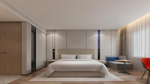 a bedroom with a large bed and a red chair at Holiday Inn Express Harbin Central Avenue by IHG in Harbin