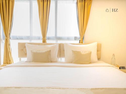 a bedroom with a white bed with two windows at Z Bliss Suites, BKC in Mumbai