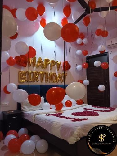 a bed with red and white balloons and a happy birthday sign at A Dream Inn Hotel in Delhi