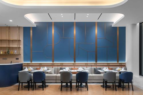 a restaurant with blue walls and tables and chairs at Holiday Inn Express Harbin Central Avenue by IHG in Harbin