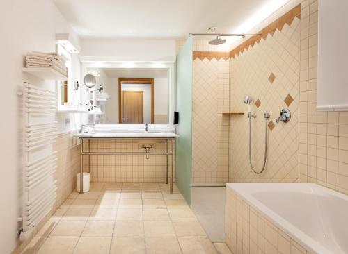 a bathroom with a tub and a sink at Kim Schlosshotel im Park in Dresden