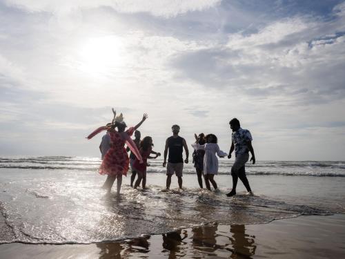 a group of people playing in the water on the beach at The Hosteller Gokarna in Gokarna