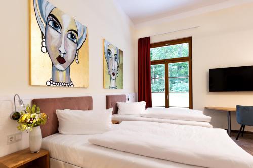 a room with three beds and a tv on the wall at Kim Schlosshotel im Park in Dresden