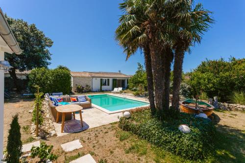 une cour avec une piscine et un palmier dans l'établissement Escapades Océanes, à Sainte-Marie de Ré