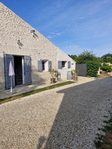 a white building with a door and a gravel road at Chambre d'hote in Saint-Dizant-du-Gua