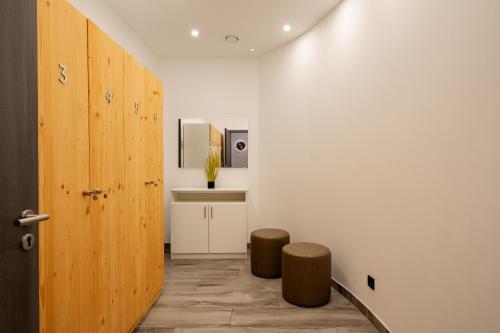 a hallway with two stools and a wooden door at Boddenflair in der Seefahrtschule in Wustrow