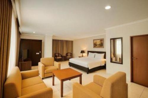 a hotel room with a bed and a living room at Plaza Hotel Tegal in Tegal