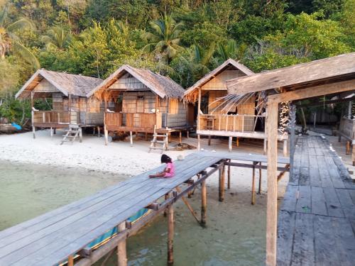 a little girl sitting on a picnic table in front of houses at byuk Beya homestay in Kri