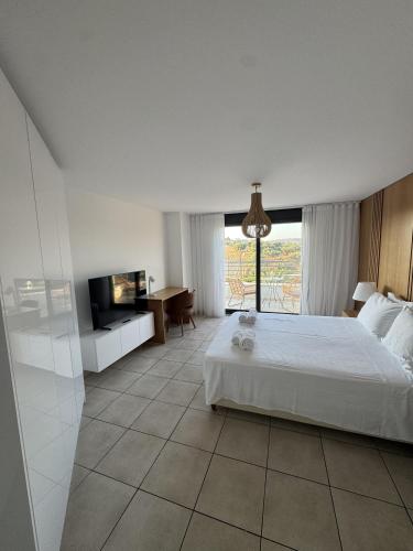 a bedroom with a white bed and a television at Possidi Hiliadou Boutique Resort in Possidi