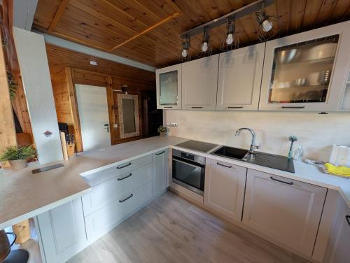 a kitchen with white cabinets and a sink at Chalet HEUREux in Somme-Leuze