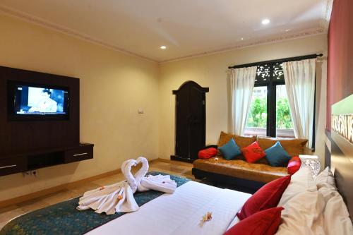 a hotel room with a bed and a tv at Puri Dewa Bharata Hotel & Villas in Legian