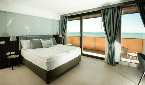 a bedroom with a bed with a view of the ocean at Hotel Europa Lignano in Lignano Sabbiadoro