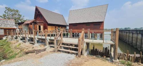 a large wooden house with a dock in front of it at RuenKijja in Ban Kroen