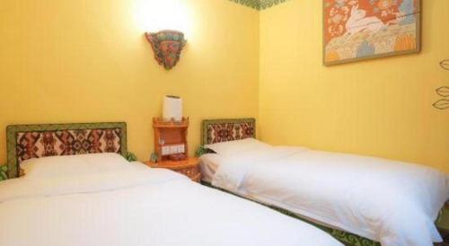 two beds in a room with yellow walls at Tashitakge Hotel in Lhasa