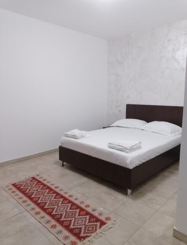 a bed in a white room with a red rug at Irina Holiday House in Mangalia