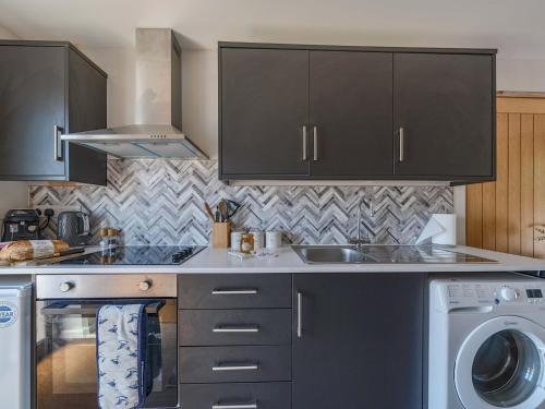 a kitchen with a sink and a washing machine at Piglet Corner in Culmstock