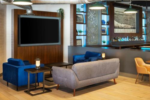 a lobby with a tv and a couch and chairs at Four Points by Sheraton Halifax in Halifax
