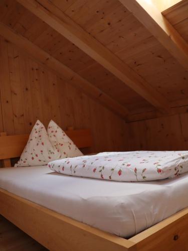 a bed with white sheets and pillows in a attic at Liebharterhof in Valdaora