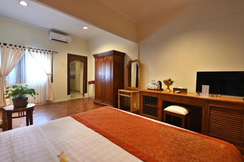 a bedroom with a bed and a flat screen tv at Puri Dewa Bharata Hotel & Villas in Legian