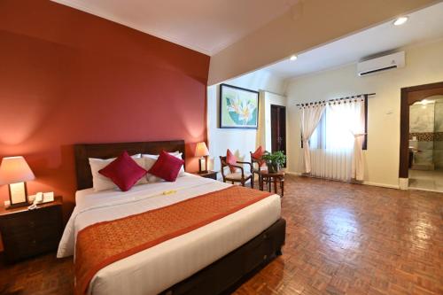 a bedroom with a large bed with red walls at Puri Dewa Bharata Hotel & Villas in Legian