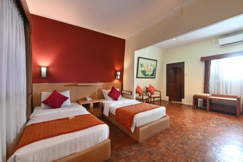 two beds in a hotel room with red walls at Puri Dewa Bharata Hotel & Villas in Legian