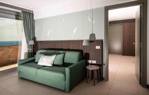 a living room with a green couch in a room at Hotel Europa Lignano in Lignano Sabbiadoro