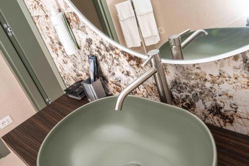 a bathroom with a green sink and a mirror at Hotel Europa Lignano in Lignano Sabbiadoro