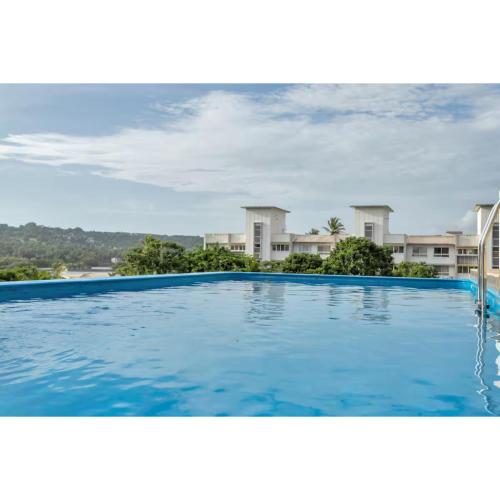 a large blue swimming pool with houses in the background at Dia Hotels and Homes Nerul Goa - Villas and Apartments in Nerul