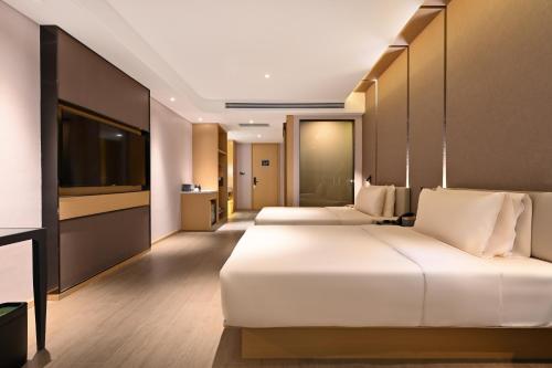 a hotel room with two beds and a flat screen tv at Atour Hotel Dalian Hi-tech Zone in Dalian