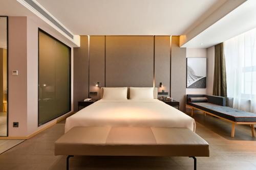 a bedroom with a large bed and a couch at Atour Hotel Dalian Hi-tech Zone in Dalian