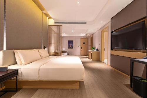 a bedroom with a large bed and a flat screen tv at Atour Hotel Dalian Hi-tech Zone in Dalian