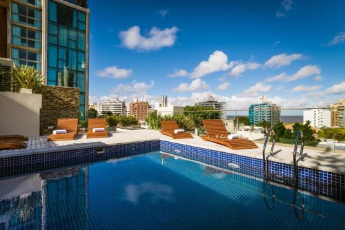 a swimming pool with lounge chairs on a building at Own Montevideo in Montevideo