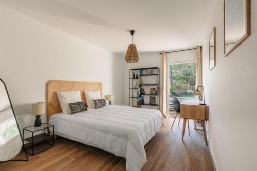 une chambre blanche avec un lit et un bureau dans l'établissement Appartement avec Jacuzzi spacieux et lumineux au cœur de Chiberta, à Anglet