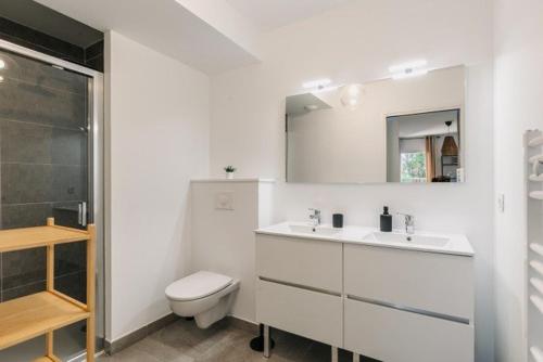une salle de bain blanche avec des toilettes et un lavabo dans l'établissement Appartement avec Jacuzzi spacieux et lumineux au cœur de Chiberta, à Anglet