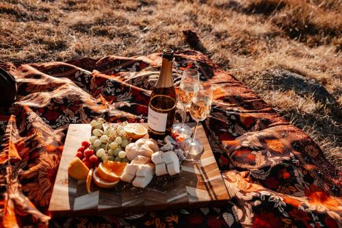 a picnic with a bottle of wine and food on a blanket at Tiny Elsie in Kalkite
