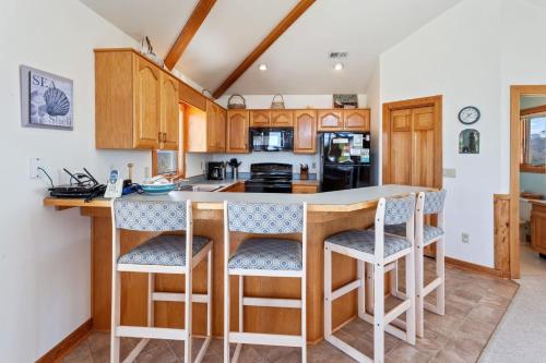 - une cuisine avec un îlot central et des tabourets de bar dans l'établissement 1300 - Shore Pleasure, à Corolla