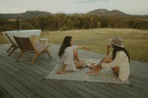 two girls sitting on a rug on a deck at Tiny Harry in Mudgee
