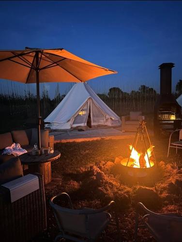 a tent and a fire in a yard with a campfire at Luxe Glamping Tipitentjes een 4 en 2 persoons tent in Echteld